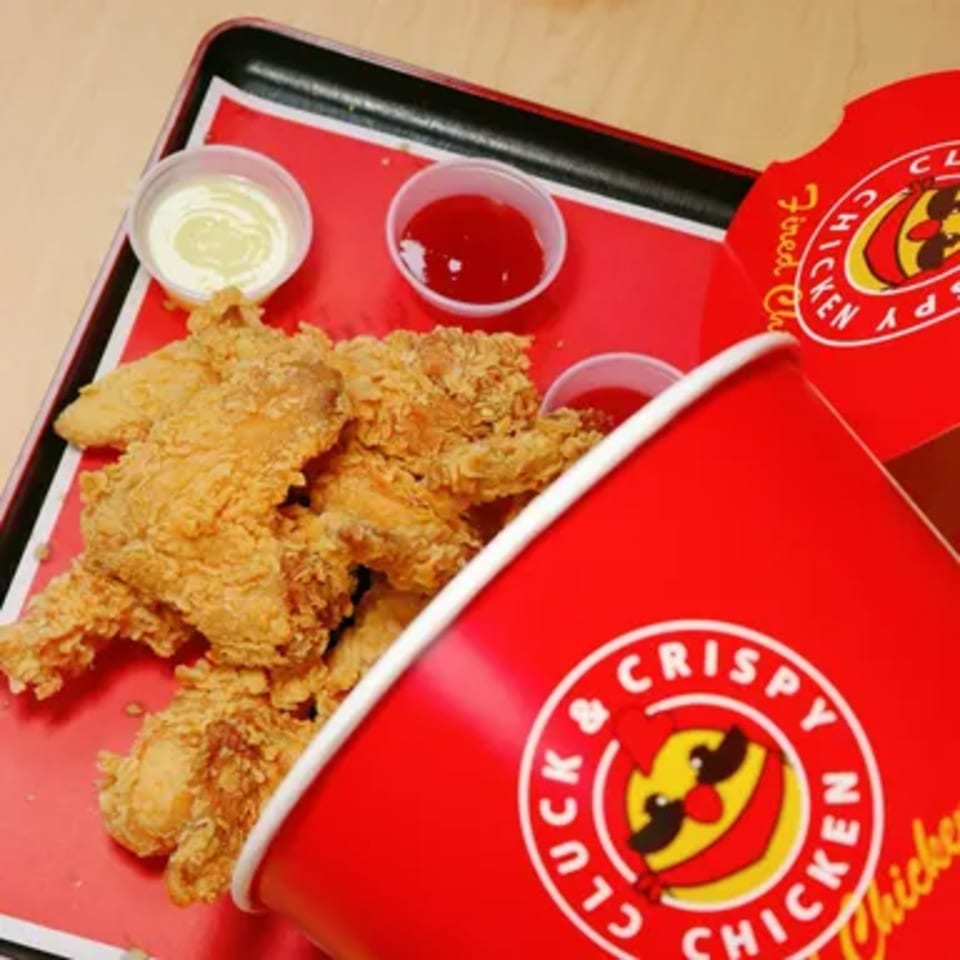 Cluck & Crispy Chicken bucket and box filled with fried chicken tenders and dipping sauces.